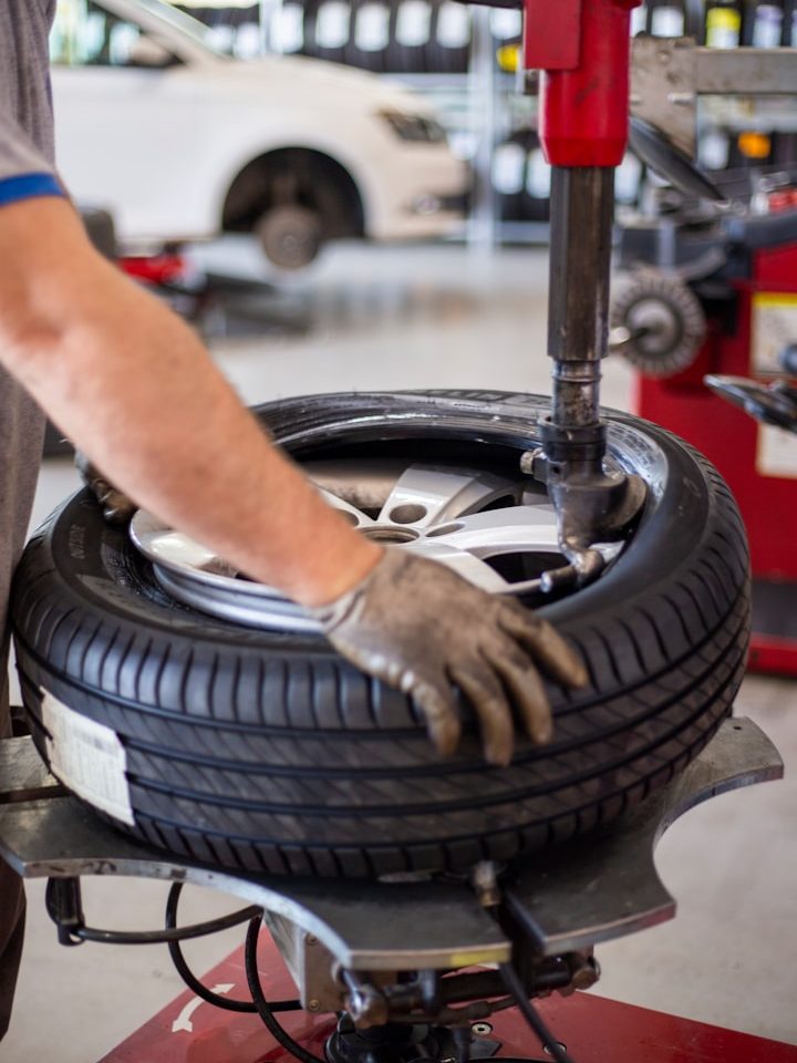 Eine Person montiert einen Reifen auf eine Alufelge in einer Werkstatt mit Hilfe einer Montiermaschine.
