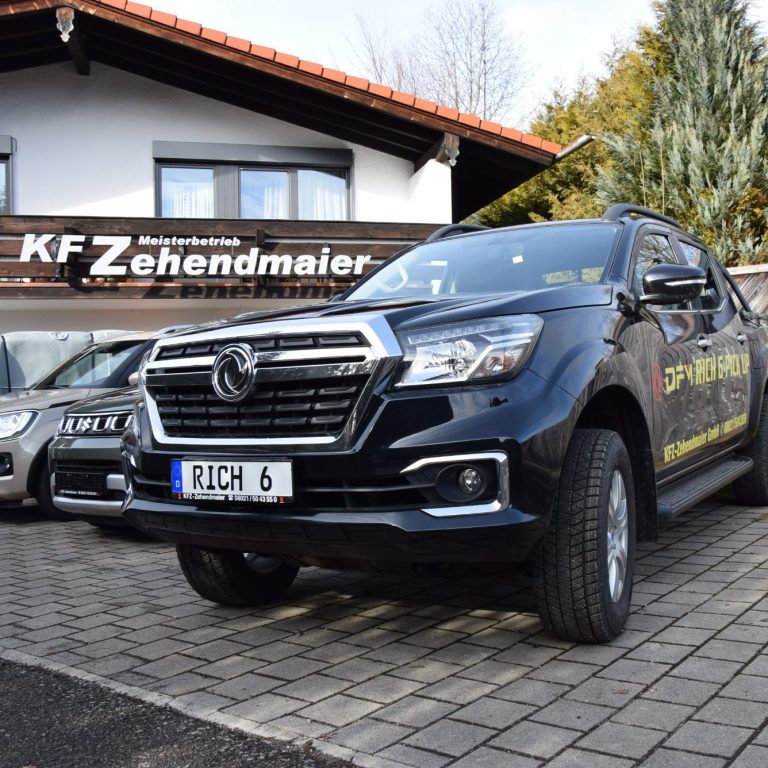 Schwarzer Pickup vor einem Autohaus mit dem Schild "KFZ-Zehendmaier".