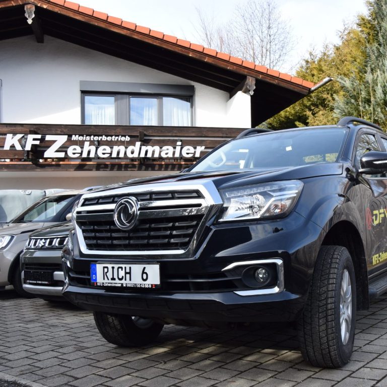 Schwarzer Pickup vor einem Autohaus mit dem Schild "KFZ-Zehendmaier".