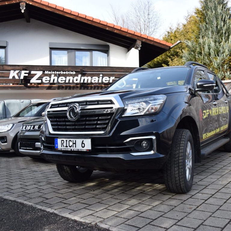Schwarzer Pickup vor einem Autohaus mit dem Schild "KFZ-Zehendmaier".