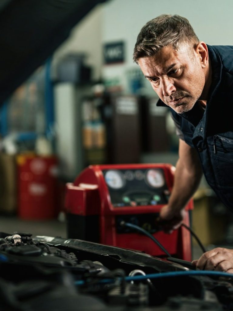 Ein Mechaniker überprüft den Motor eines Autos in einer Werkstatt.