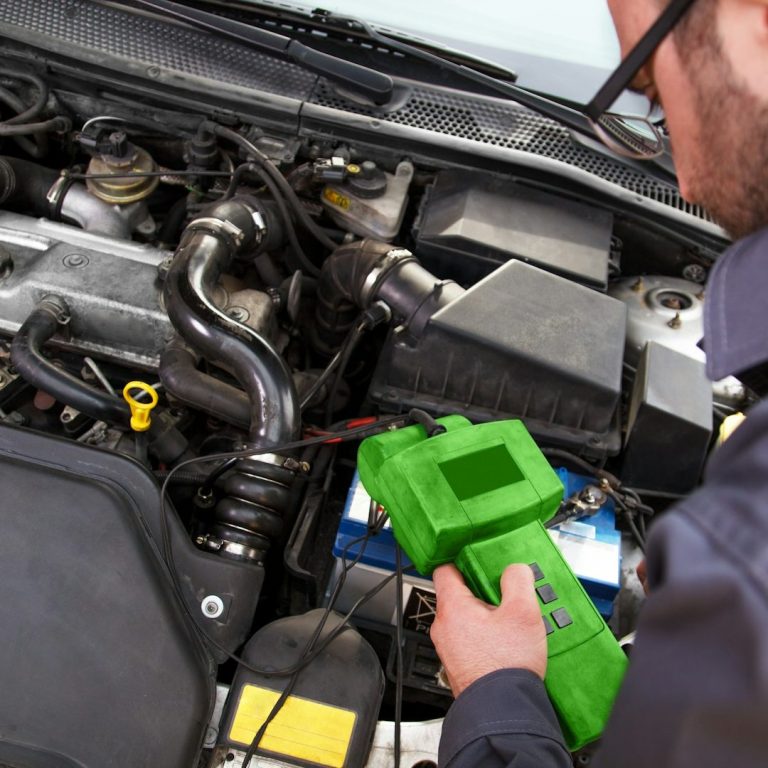 Mechaniker prüft Autokomponenten mit einem grünen Diagnosetool.