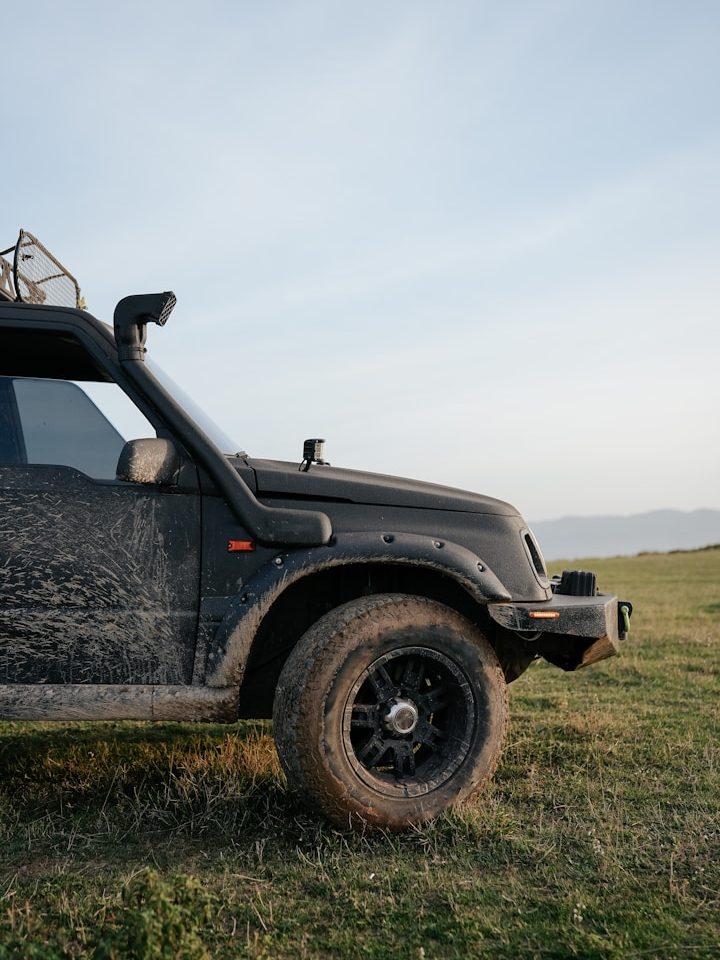 Schwarzes Geländefahrzeug auf einer grünen Wiese im Freien.