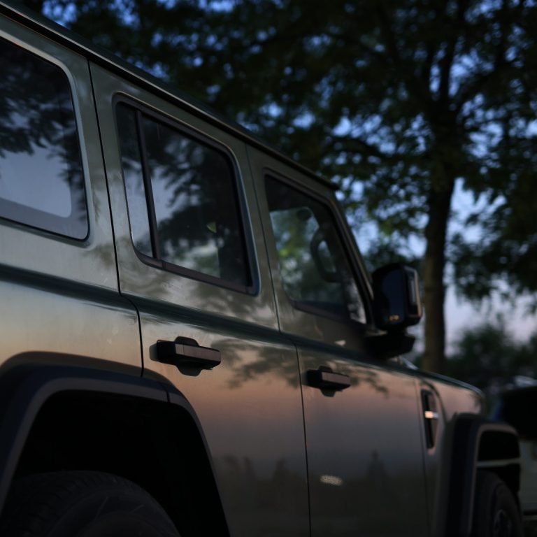 Geländewagen in olivgrüner Farbe, robustes Design mit viereckiger Karosserie.