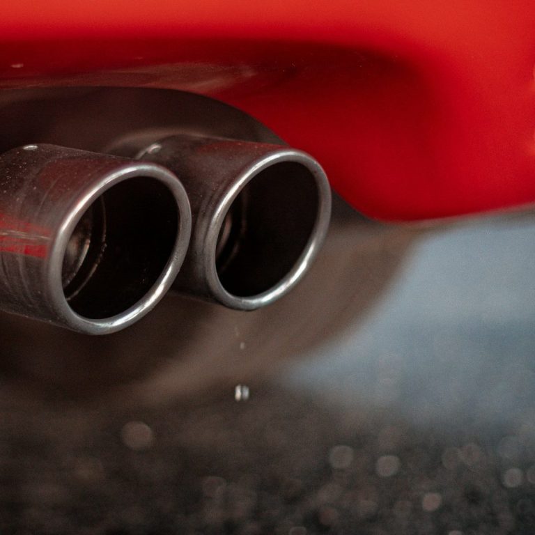 Doppelter Auspuff eines Sportwagens mit Wassertröpfchen, die herabfallen.