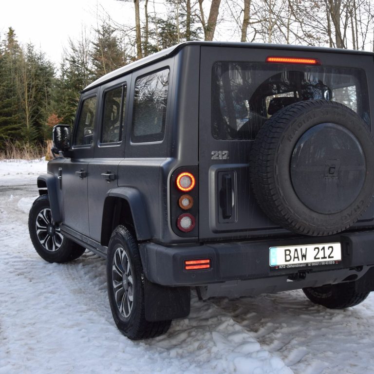 Geländewagen in olivgrüner Farbe, robustes Design mit viereckiger Karosserie.