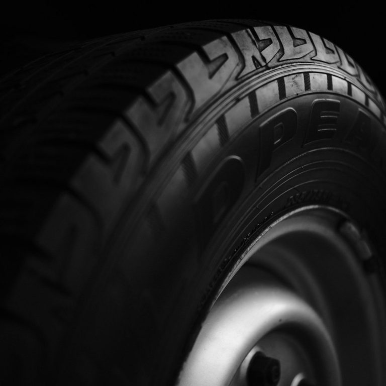 Nahaufnahme eines Autoreifens mit gutem Profil vor dunklem Hintergrund.