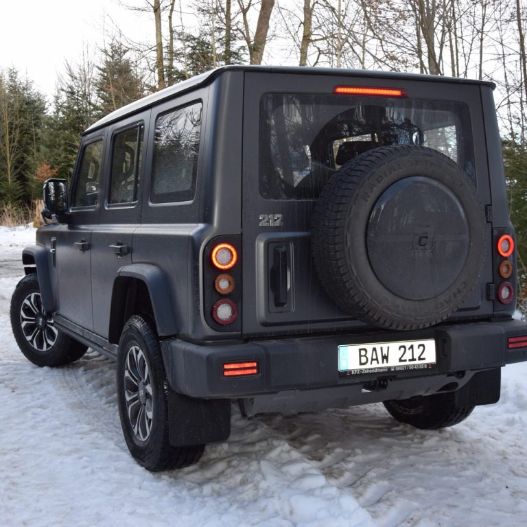 Geländewagen in olivgrüner Farbe, robustes Design mit viereckiger Karosserie.